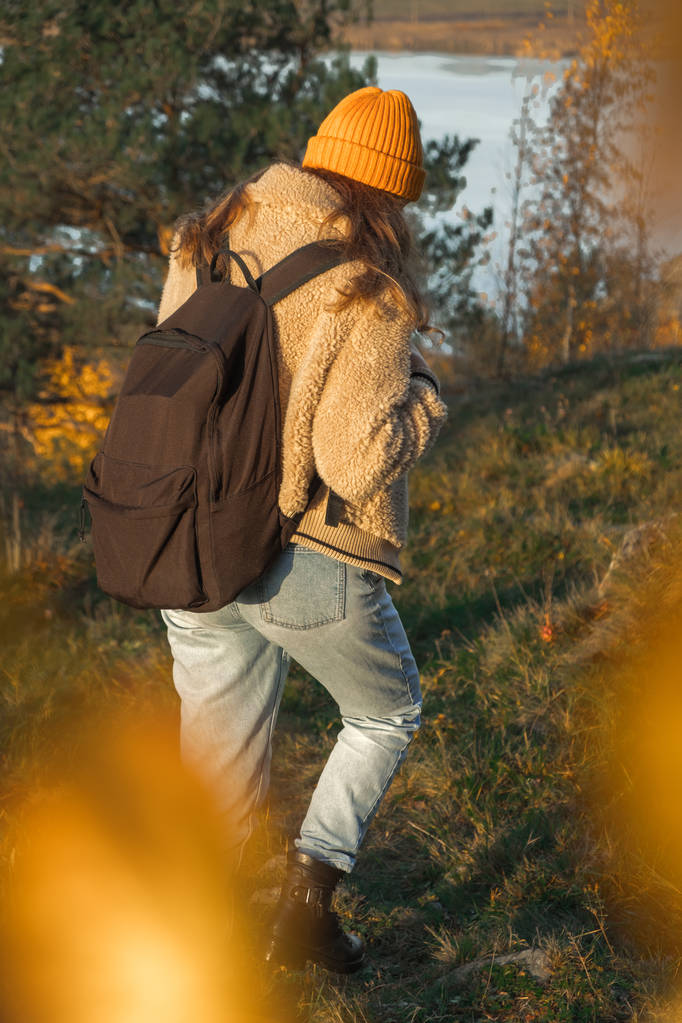 Chica joven Hipster con mochila disfrutando de la puesta de sol en el pico de la montaña brumosa. Viajero turístico en la maqueta de vista de fondo. Caminante mirando la luz del sol en viaje
 - Foto, Imagen