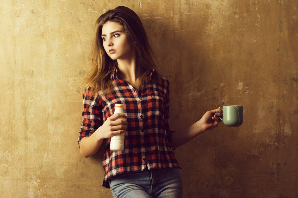 Mooi meisje holding fles en cup met kefir - Foto, afbeelding