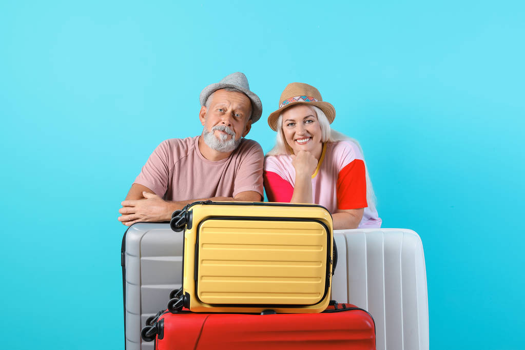 Старшая пара с чемоданами на цветном фоне. Отдых
 - Фото, изображение