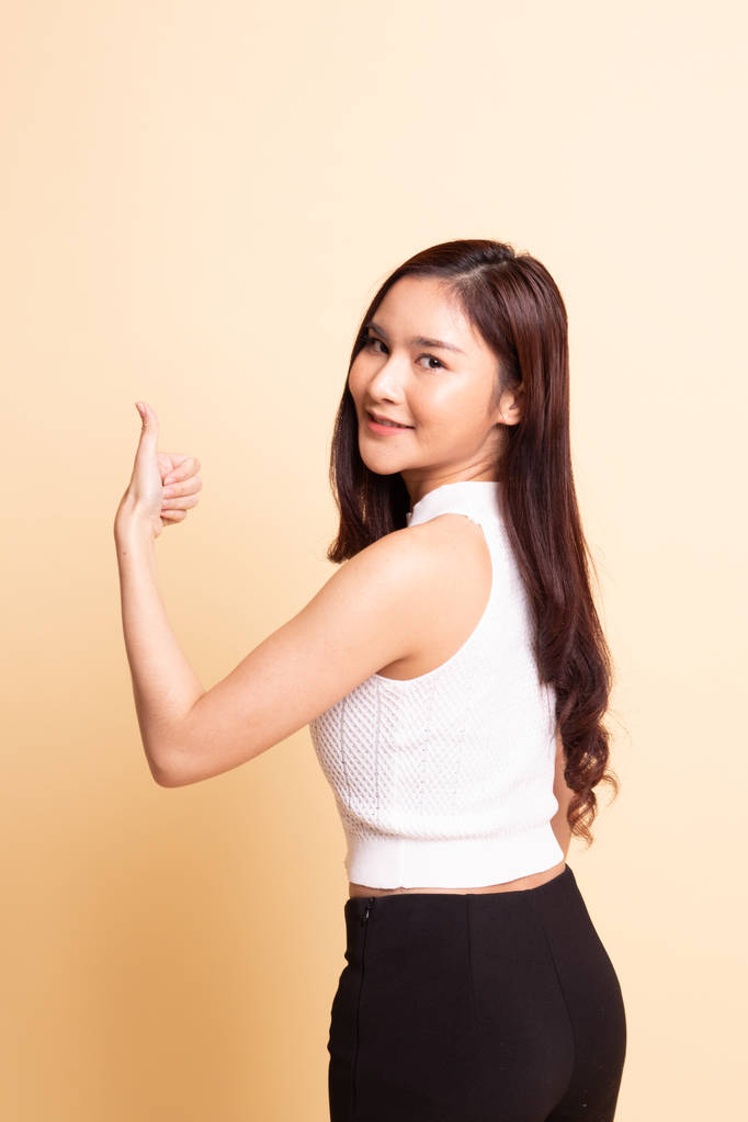 Genç Asyalı kadın bej arka planda baş parmağını kaldırdı. - Fotoğraf, Görsel