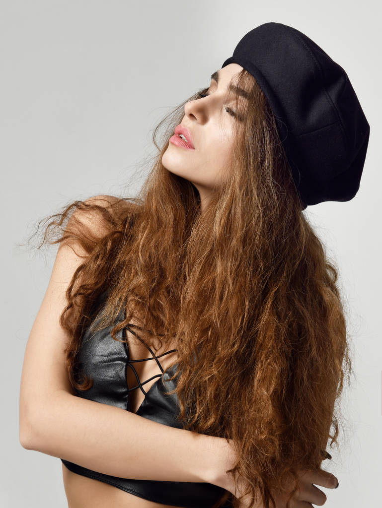 Mladá sexy brunetka žena v hnědých baret klobouk při pohledu na rohu  - Fotografie, Obrázek