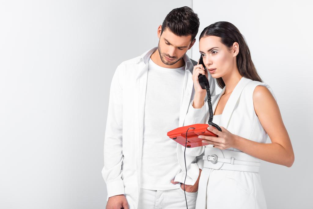 доросла пара в цілому біла з старовинним червоним телефоном, що відповідає на дзвінок
 - Фото, зображення