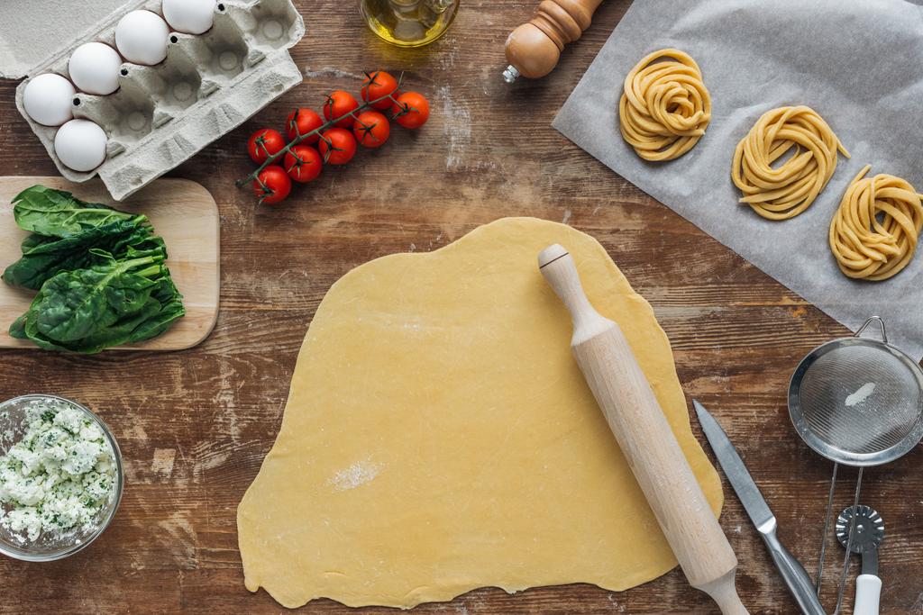 vista dall'alto della pasta cruda con mattarello e ingredienti della pasta sul tavolo di legno
 - Foto, immagini