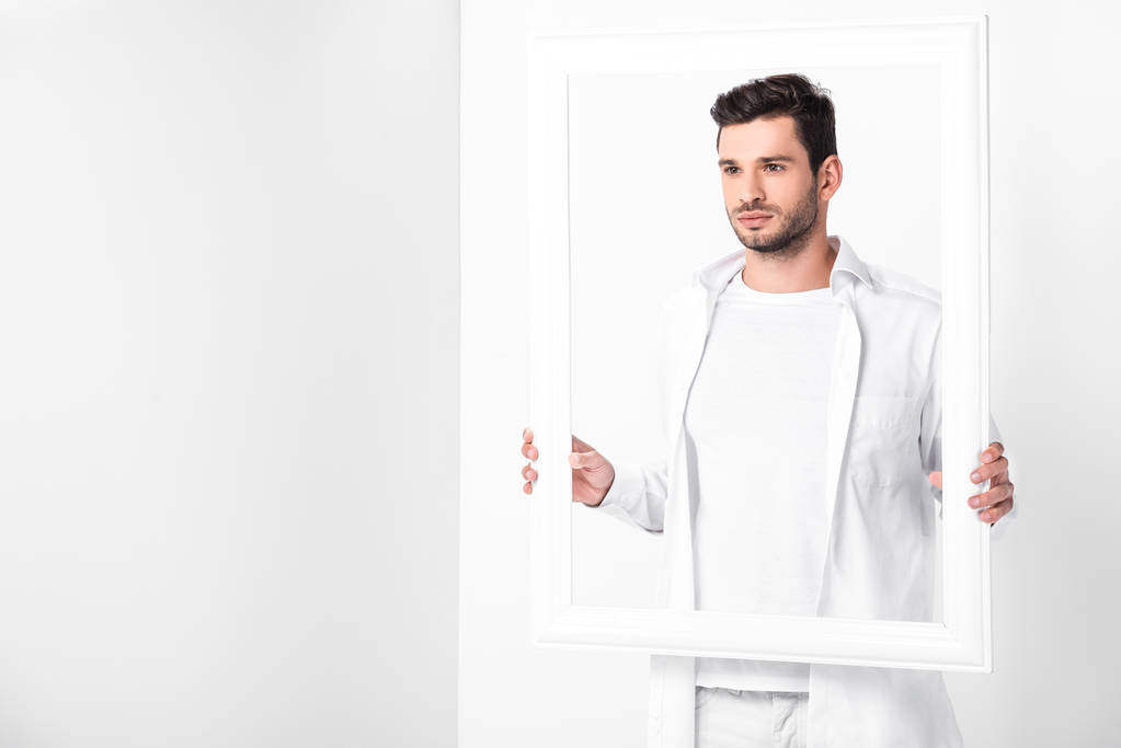 guapo adulto hombre en total blanco posando con marco
  - Foto, Imagen