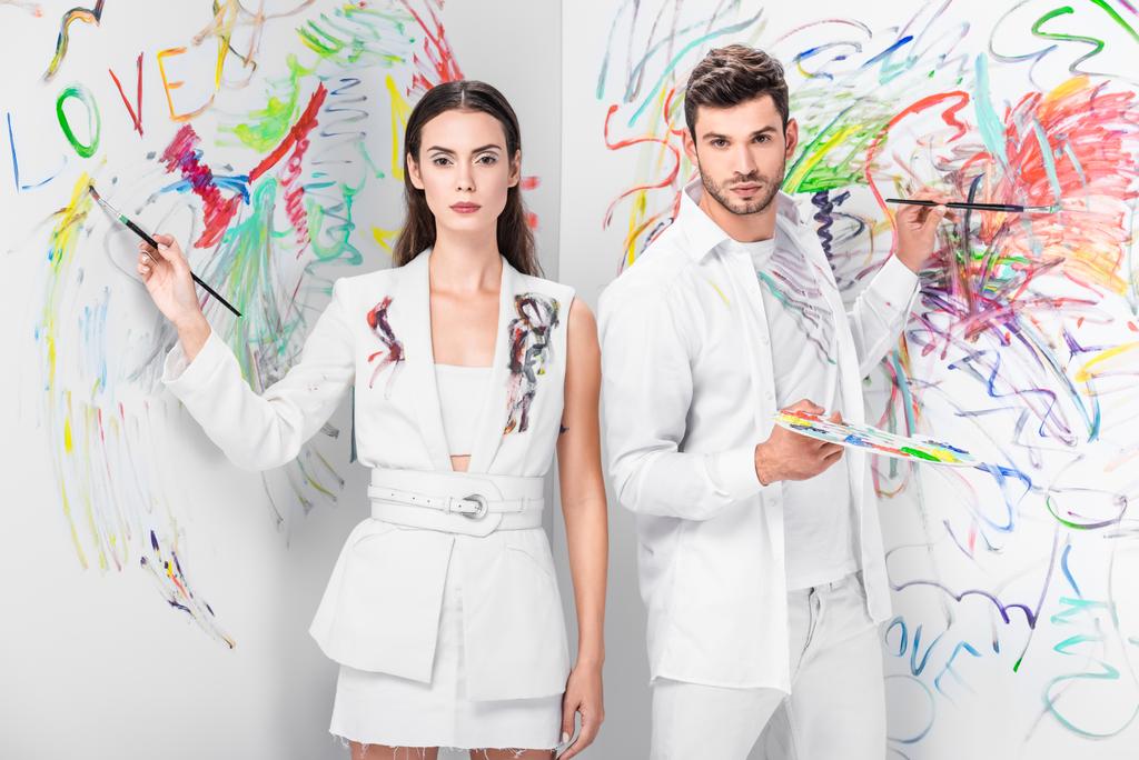 fashion shoot of couple in total white drawing with paints on wall - Photo, Image