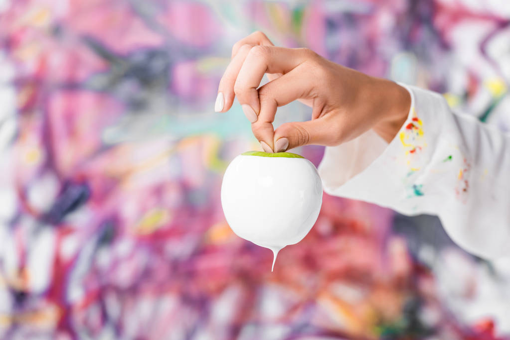 lähikuva naisten käsi tilalla valkoinen maalattu omena
 - Valokuva, kuva