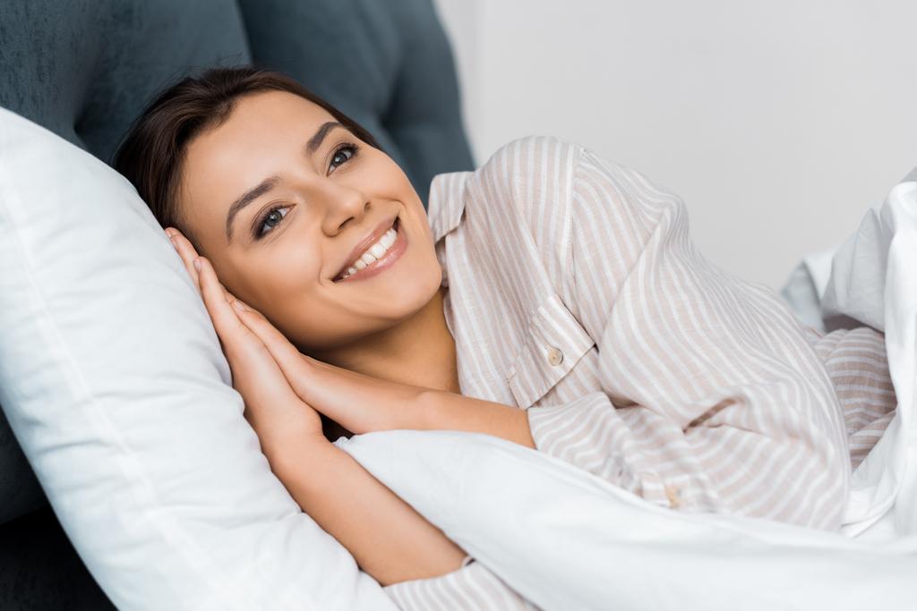 hermosa chica sonriente en pijama relajarse en la cama
 - Foto, Imagen