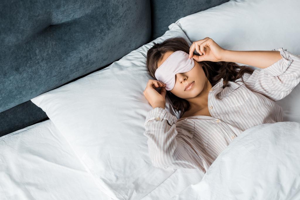 mujer joven con máscara para dormir despertando en la cama por la mañana
 - Foto, Imagen