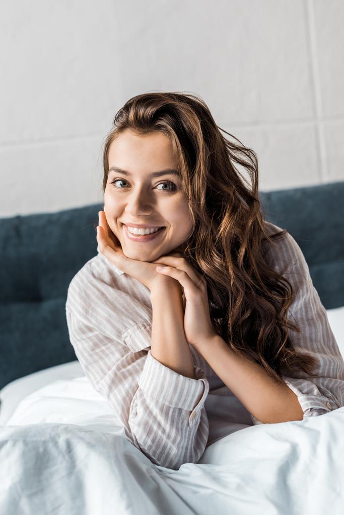 joyeuse jeune femme regardant la caméra et assise sur le lit le matin
 - Photo, image