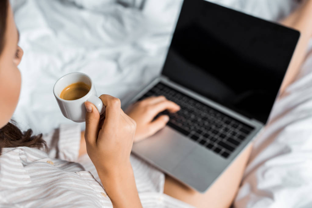 vista cortada de menina com café usando laptop com tela em branco na cama
 - Foto, Imagem