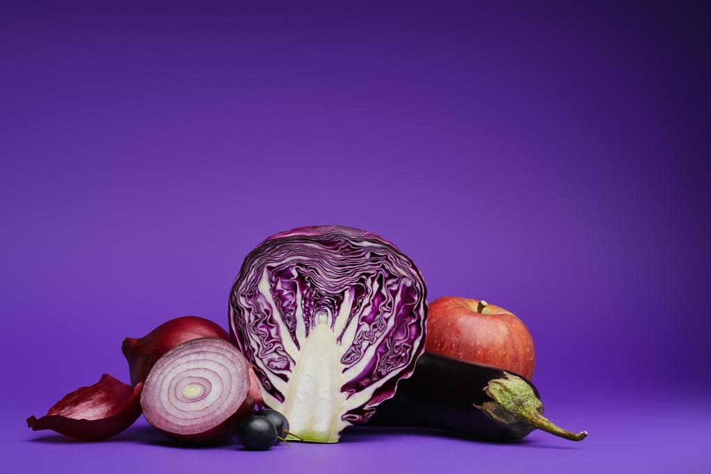 close-up view of sliced cabbage, onions, grapes, eggplant and apple on purple - Photo, Image