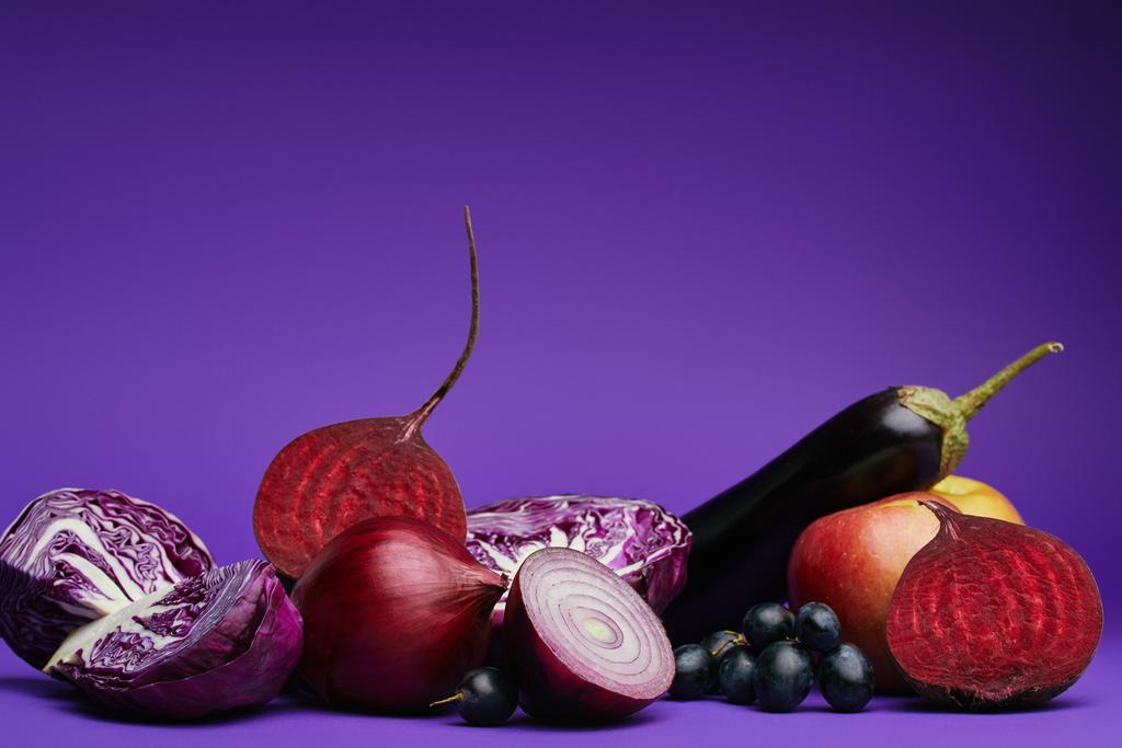 γκρο πλαν θέα λάχανο κομμένο σε φέτες, τα κρεμμύδια, παντζάρια, σταφύλια, μήλο και μελιτζάνες σε μωβ  - Φωτογραφία, εικόνα