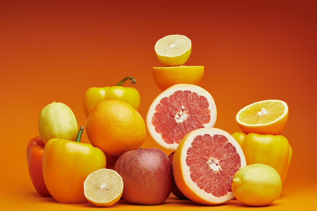 свіжі стиглі цитрусові та болгарські перці на помаранчевому фоні
   - Фото, зображення