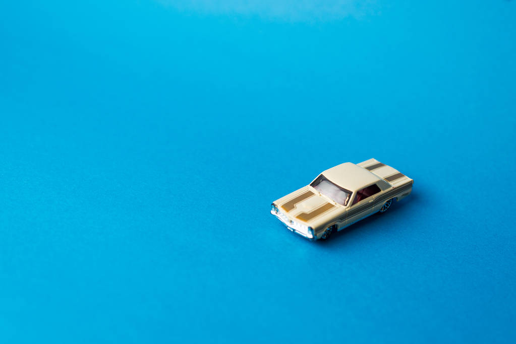Close-up van speelgoedauto op blauwe achtergrond, minimalistische concept - Foto, afbeelding