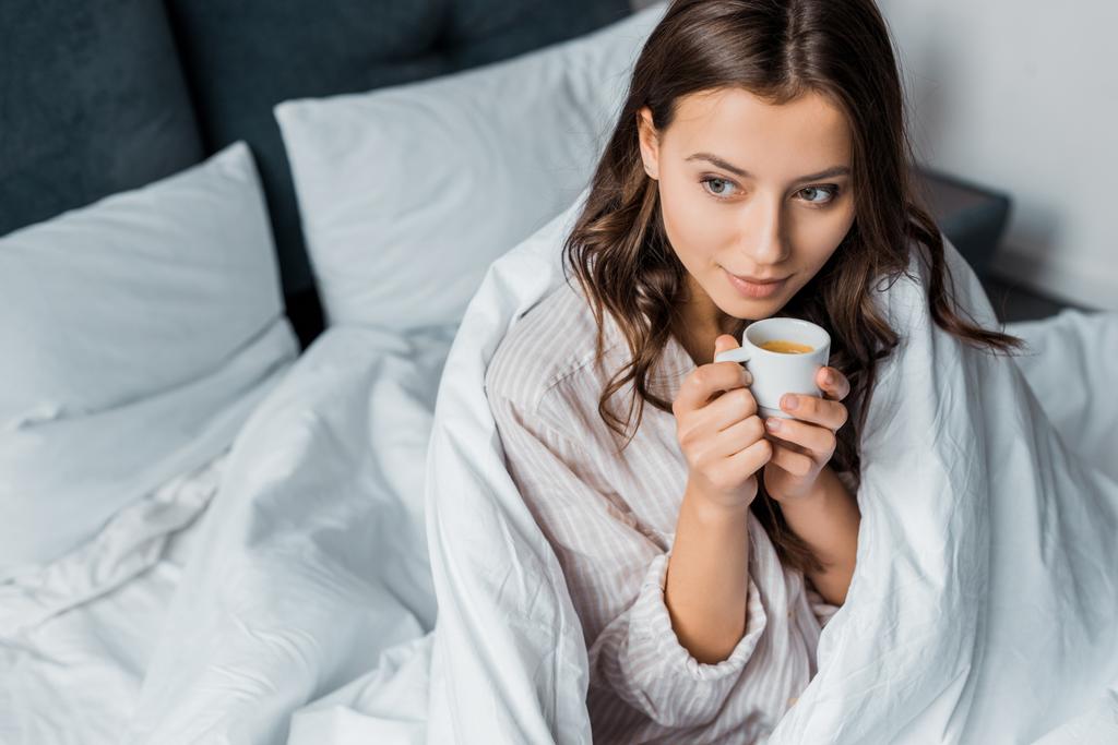 mooi peinzende meisje met koffie in bed in de ochtend - Foto, afbeelding