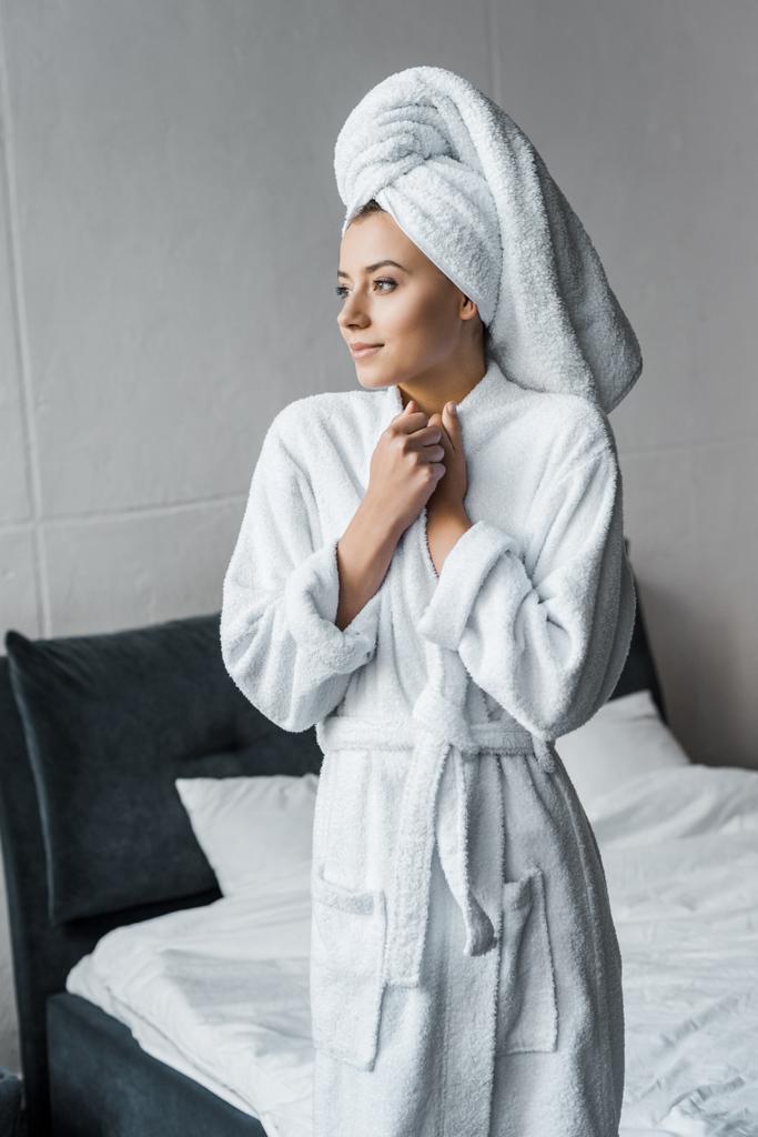beautiful dreamy woman in white bathrobe and towel standing in bedroom - Photo, Image