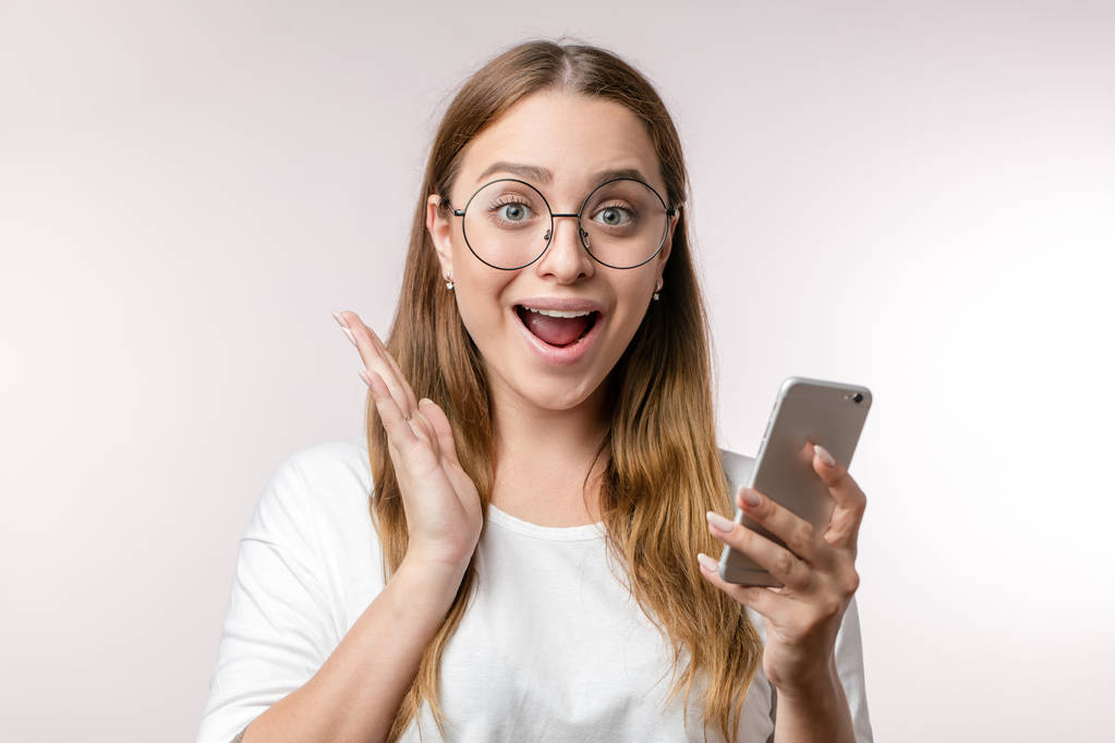 mujer asustada ansiosa en gafas redondas con teléfono inteligente
 - Foto, Imagen
