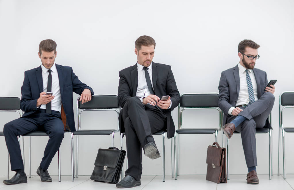άνθρωποι των επιχειρήσεων με τα κινητά τηλέφωνα που κάθεται στο γραφείο διάδρομο - Φωτογραφία, εικόνα