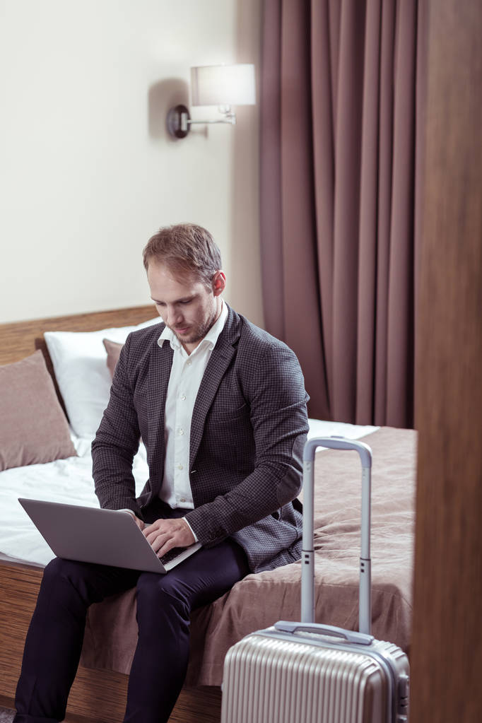 Бізнесмен працює на своєму ноутбуці, перш ніж покинути готельний номер
 - Фото, зображення