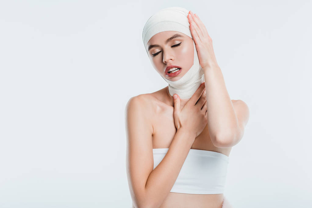 volwassen mooie vrouw na plastische chirurgie aan hoofd op wit wordt geïsoleerd te raken - Foto, afbeelding