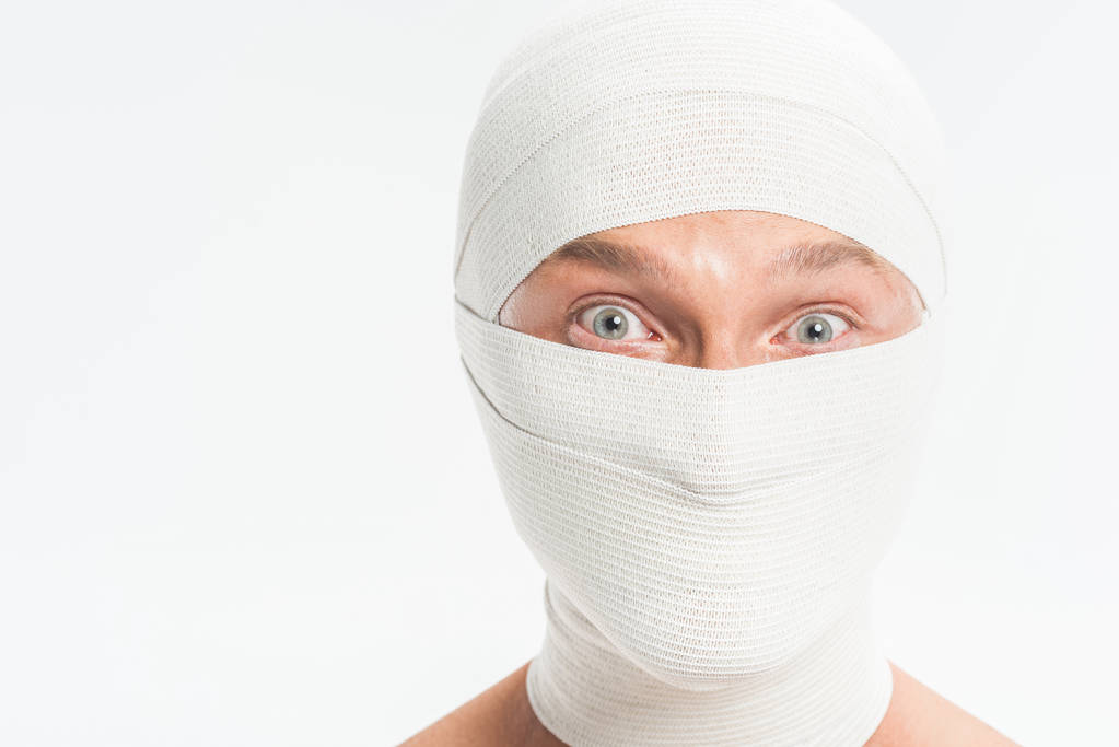 Nahaufnahme des Gesichts des Mannes mit weißen Binden bedeckt nach einer plastischen Operation isoliert auf weiß - Foto, Bild