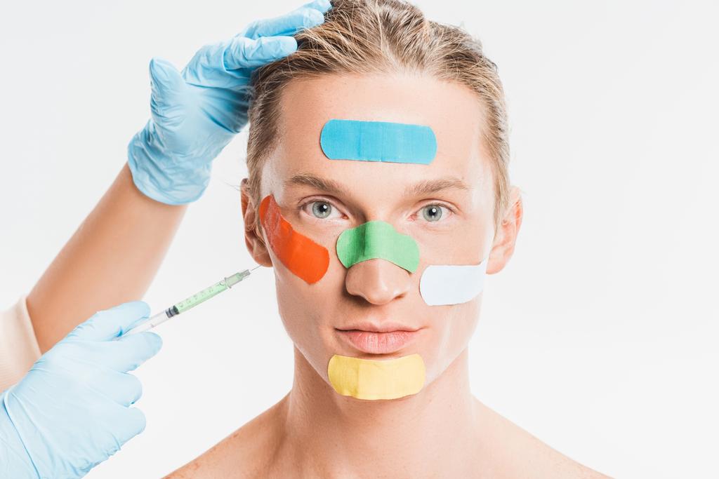 白で隔離の顔に色とりどりのパッチを持つ男に注射を行う医師 - 写真・画像
