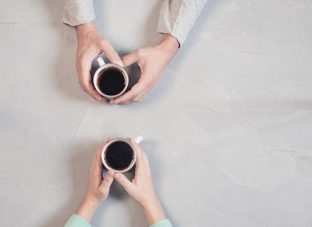 Paar verliefd hand in hand met koffie op witte marmeren tafel. Foto genomen van bovenaf, top uitzicht met kopie ruimte - Foto, afbeelding