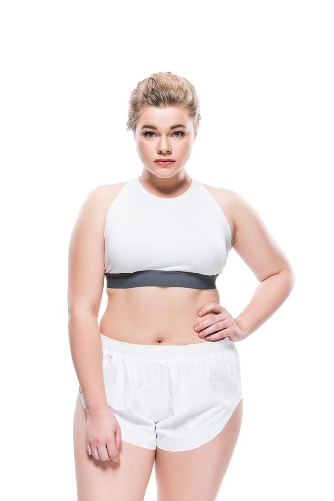 young oversize woman in sportswear standing with hand on waist and looking at camera isolated on white  - Photo, Image