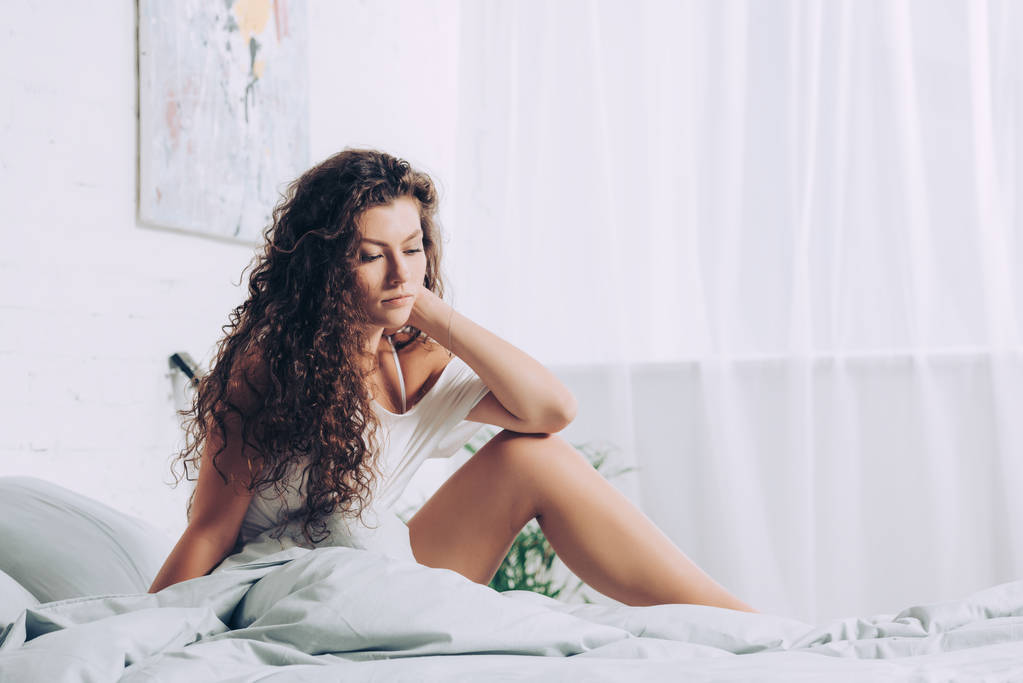 pěkně kudrnatá dívka pózuje v posteli během ranní čas doma - Fotografie, Obrázek