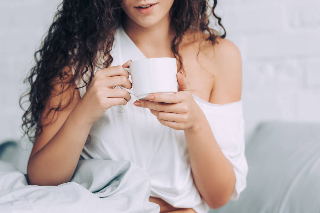 vista parcial da mulher bebendo café na cama durante o horário da manhã em casa
 - Foto, Imagem