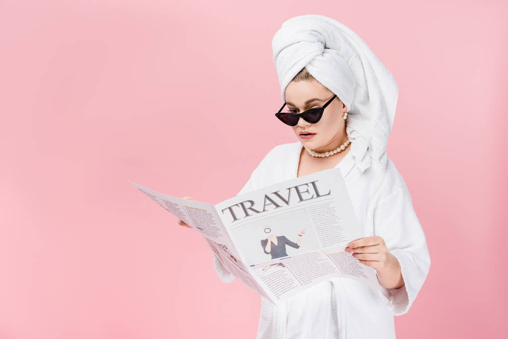 fiatal méretét, valamint nő a napszemüveg, fürdőköpeny és törölköző rózsaszín elszigetelt utazási újság olvasó fej - Fotó, kép