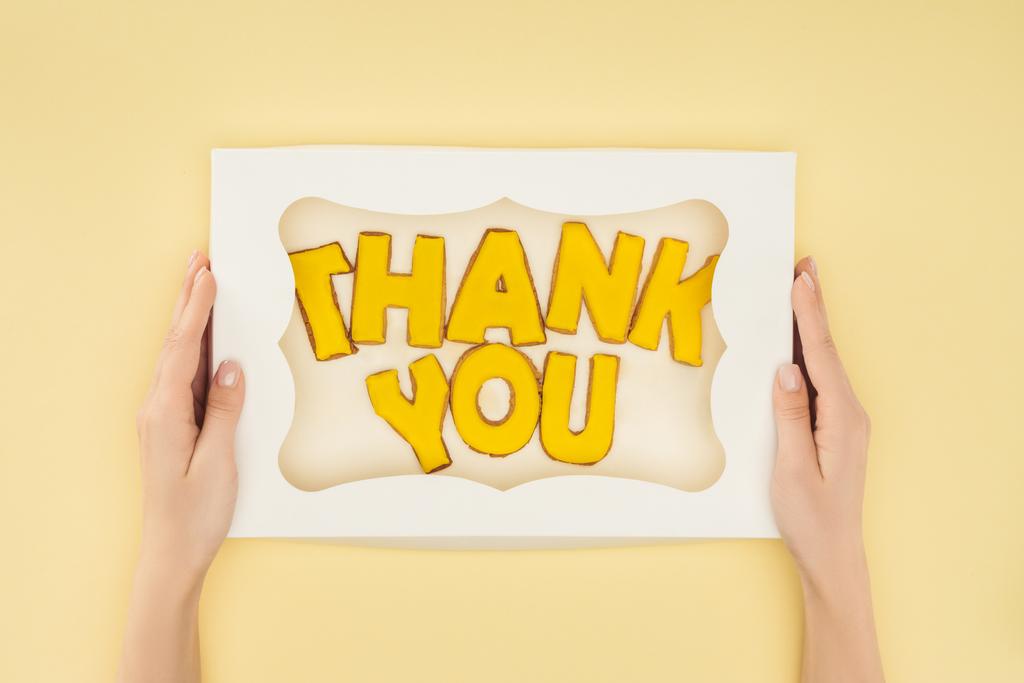 cropped person holding square-shaped cake in box with thank you lettering isolated on yellow background - Photo, Image