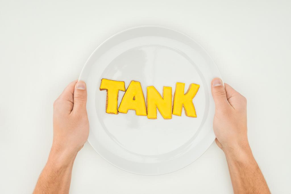 cropped person holding plate with tank word in yellow cookies isolated on white background - Photo, Image