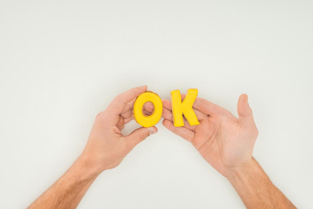 cropped person holding ok word in yellow cookies solated on white background - Photo, Image
