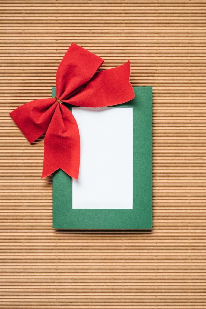 top view of green christmas frame with red bow on textured background - Photo, Image