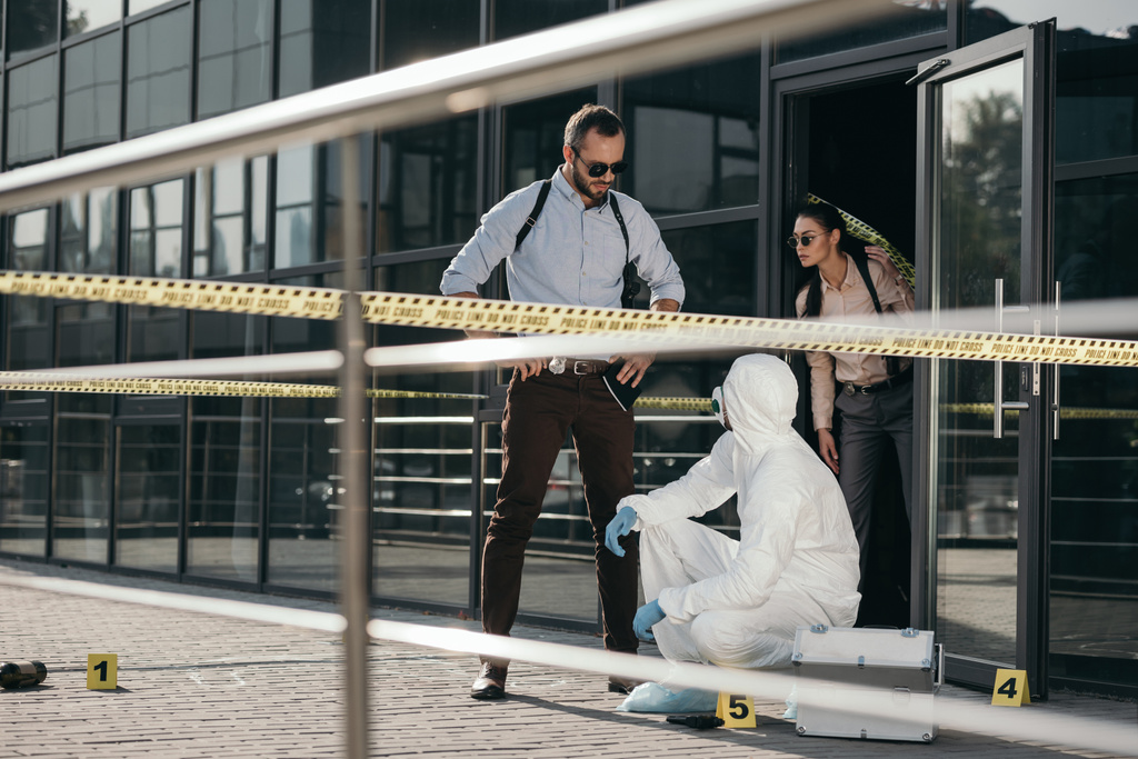detectives y criminólogos en traje protector y guantes de látex que se comunican en la escena del crimen
 - Foto, imagen