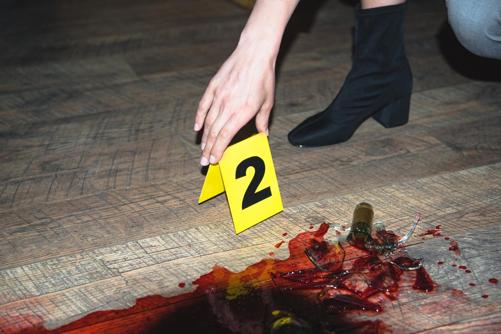 περικοπεί άποψη του χέρι αγγίζει αποδεικτικά στοιχεία σήματος στο αιματηρό έγκλημα σκηνή - Φωτογραφία, εικόνα