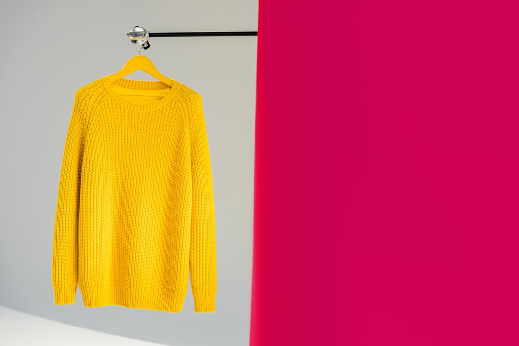 ハンガー ピンクと灰色の背景の上に黄色いニット セーターを着て - 写真・画像