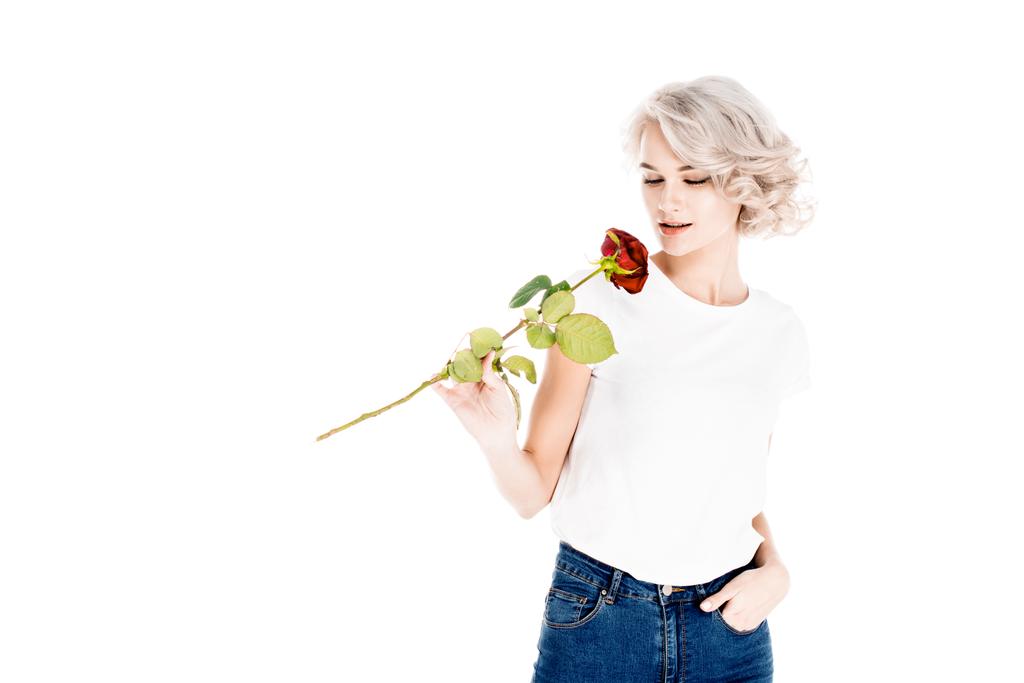 Prachtige jonge volwassen vrouw ruiken rode roos geïsoleerd op wit - Foto, afbeelding