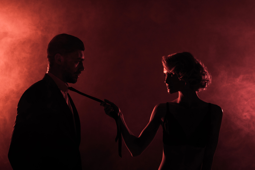 sensual mulher puxando homem por gravata no vermelho fumaça fundo
 - Foto, Imagem