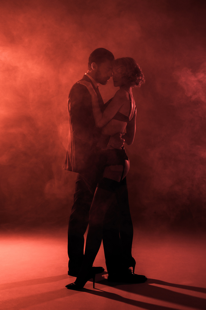 Gyönyörű pár átölelve, és szinte megcsókolta a vörös füst háttér - Fotó, kép