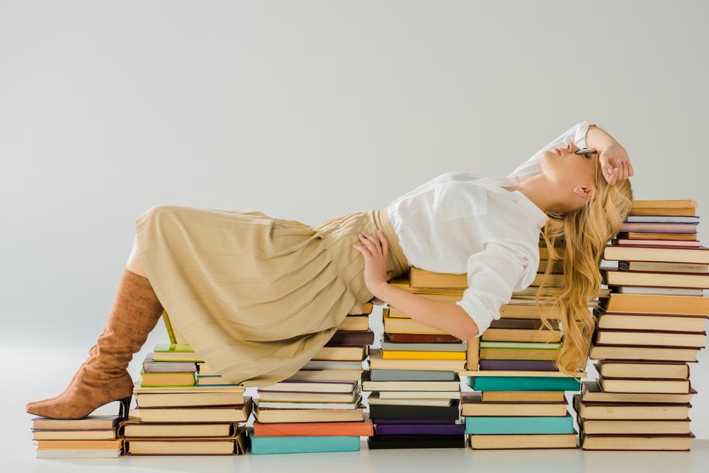 beautiful blonde woman in glasses posing on pile of retro books - Photo, Image