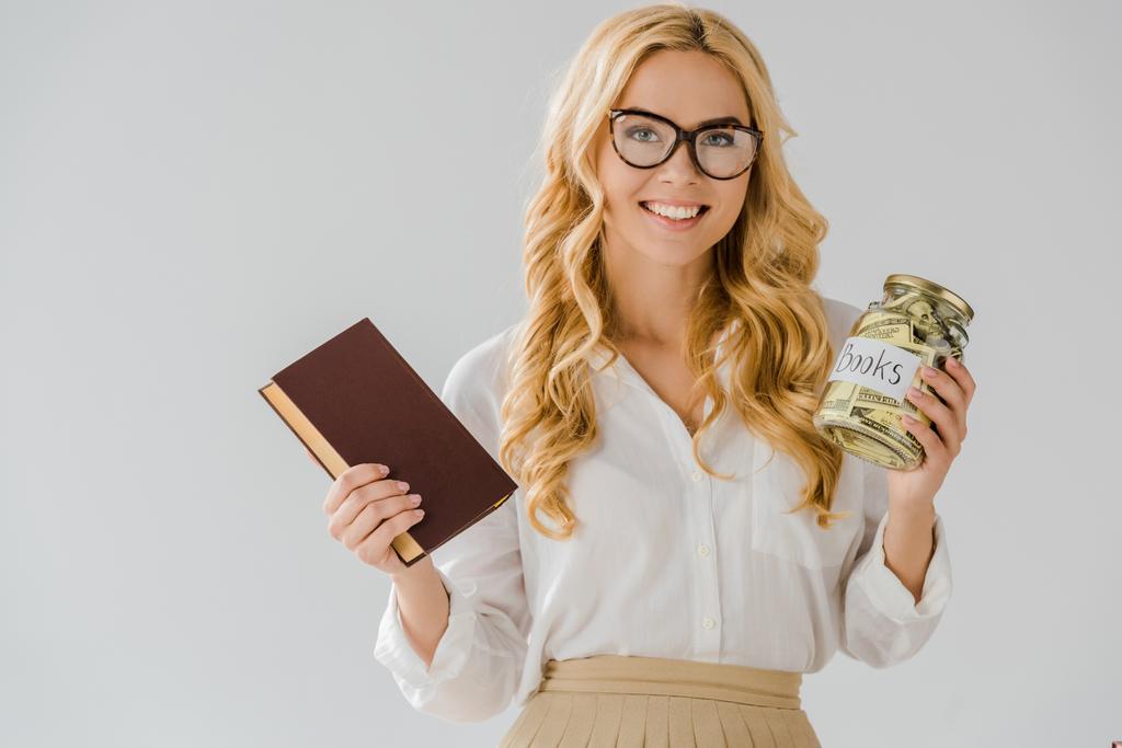 beautiful woman in glasses with book and savings in jar isolated on grey  - Photo, Image