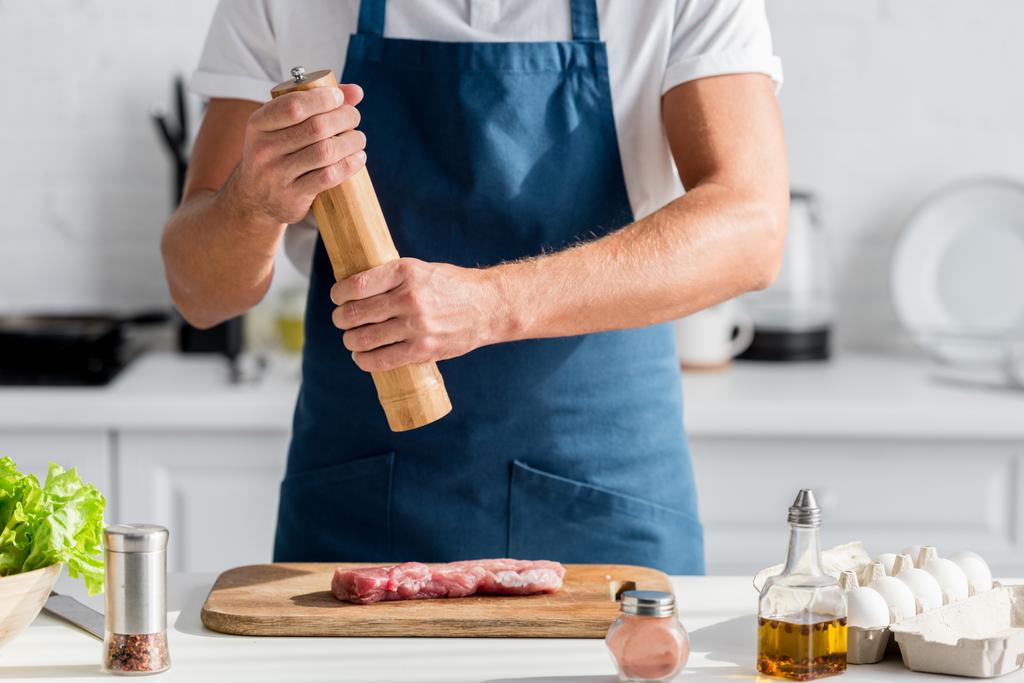 обрізаний вид чоловіка приправляє м'ясо на вечерю
 - Фото, зображення