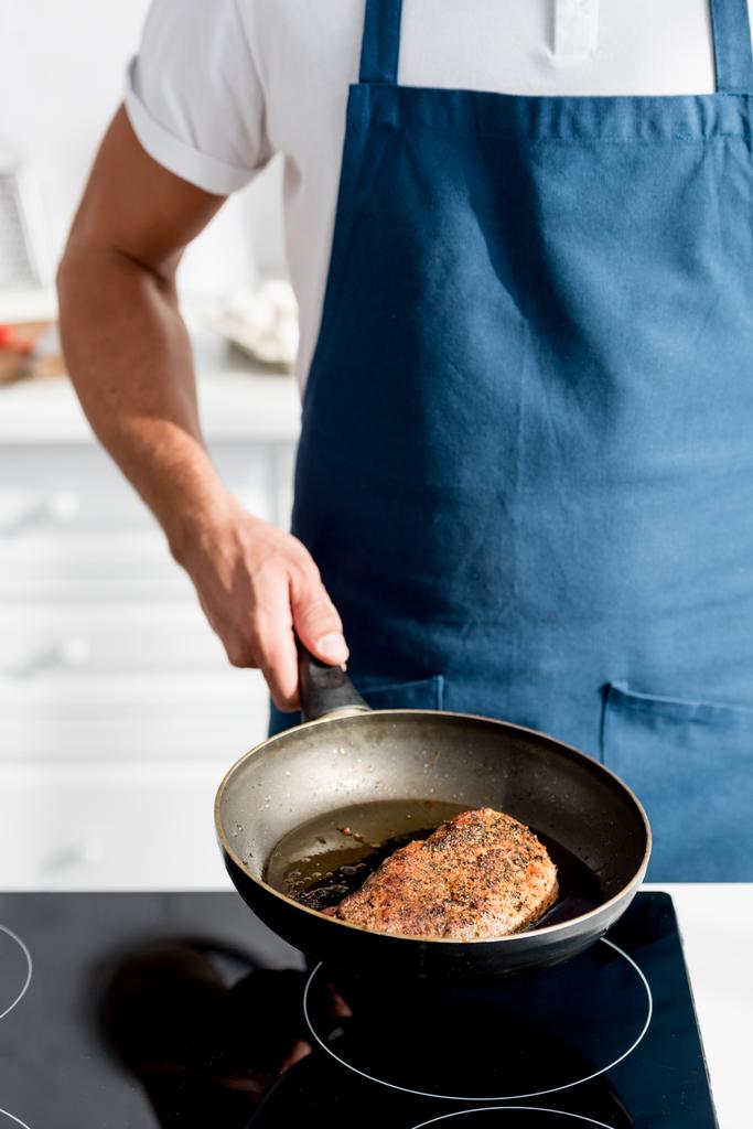 partial view of man holding pan with cooked steak - Photo, Image