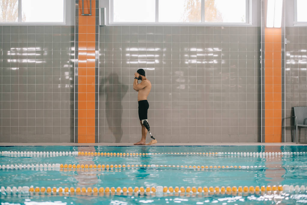 przystojny młody sportowiec z sztucznych nóg stojąc na basenie krytym basenie - Zdjęcie, obraz