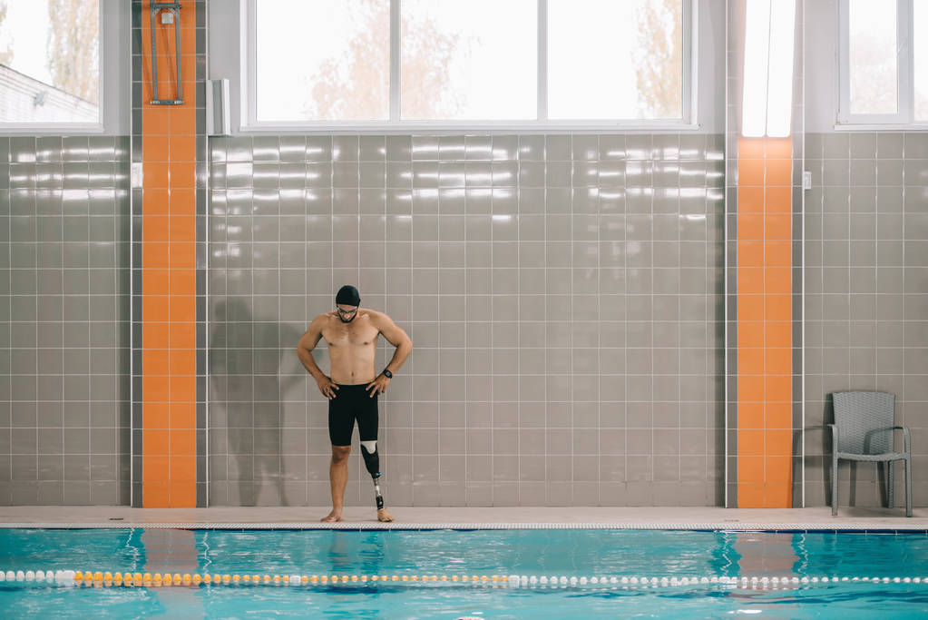 svalnatý mladý sportovec s umělou nohou stojící na bazénu na krytý plavecký bazén - Fotografie, Obrázek