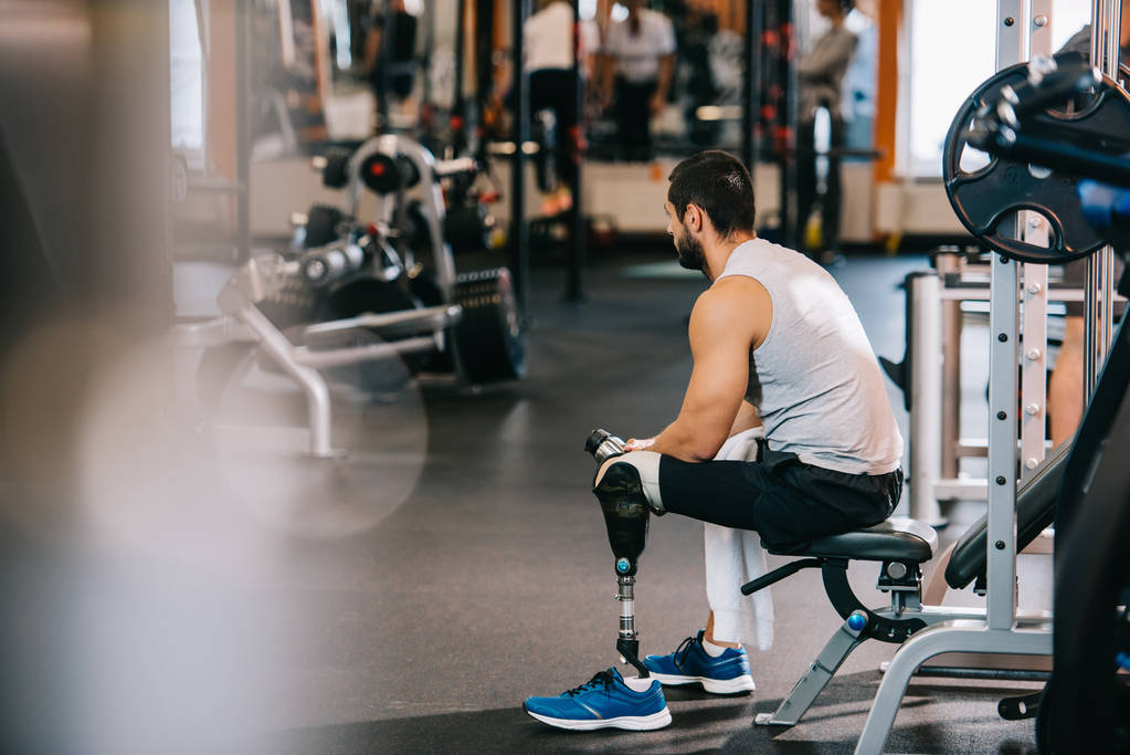 перевантажений спортсмен зі штучною ногою сидить у спортзалі
 - Фото, зображення