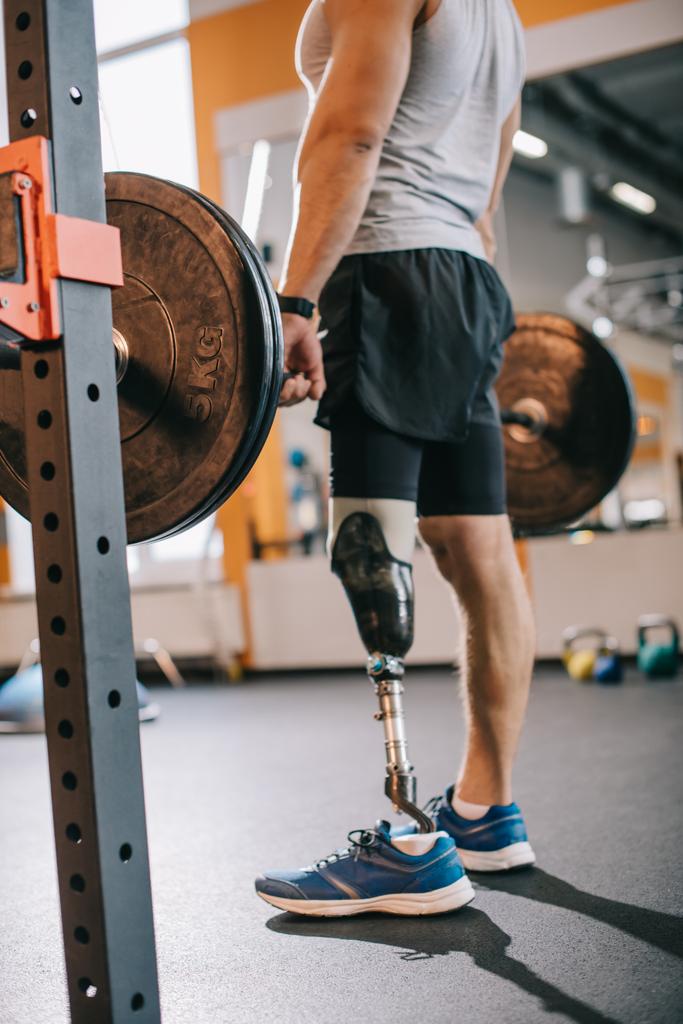 περικοπεί βολή του fit αθλητή με τεχνητό πόδι εργάζονται έξω με barbell στο γυμναστήριο - Φωτογραφία, εικόνα