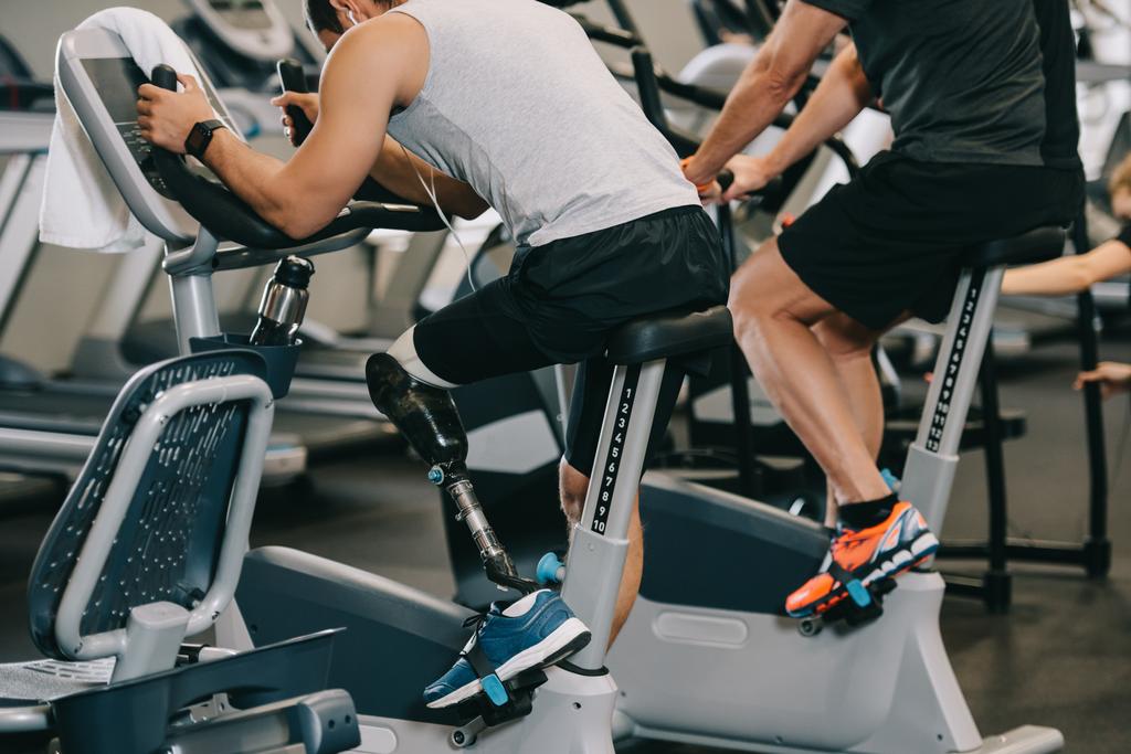 αθλητής με τεχνητό πόδι που εργάζονται έξω σε στατικό ποδήλατο στο γυμναστήριο - Φωτογραφία, εικόνα